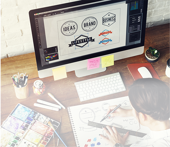 Girl working on a logo design at her desk, in front of her computer.