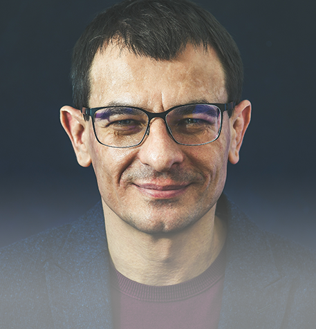 Older male with glasses smiling at the camera.