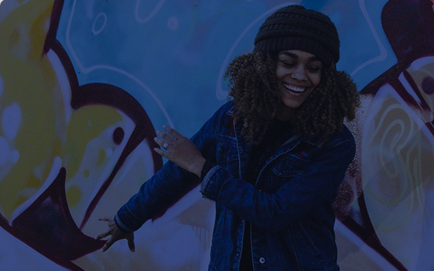 African American girl laughing while dapping in-front of a mural.