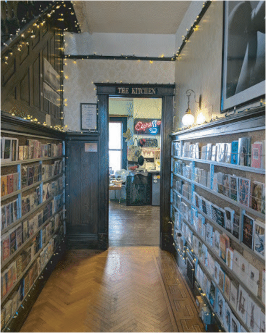 The main interior hallway of the store is shown. The hallway is lined with greeting cards available for purchase and the back part of the store is barely visible through the open doorframe.