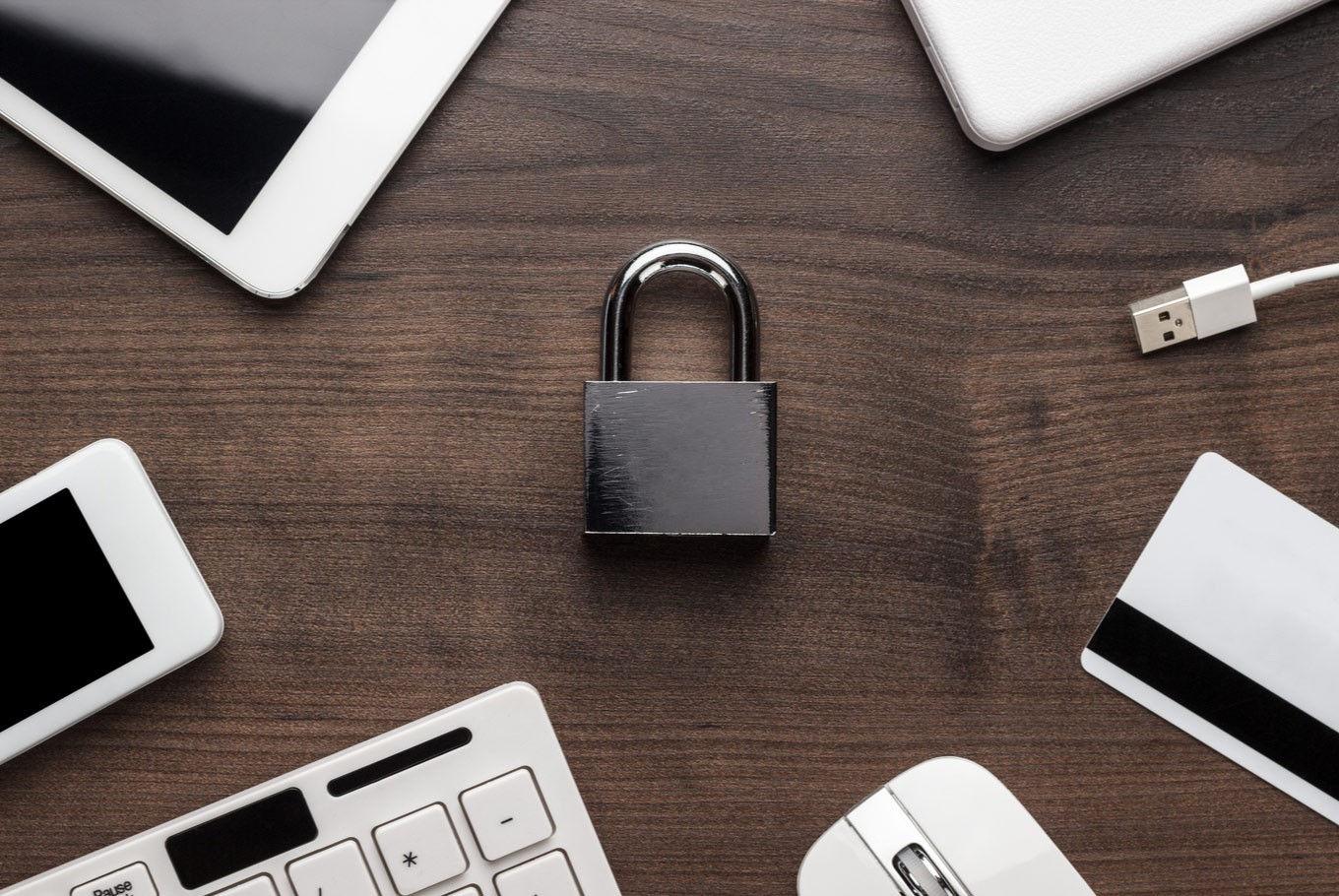 A photo of a padlock surrounded by electronics on a desk