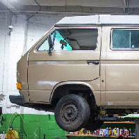 beige volkswagen westfalia camper van high on life and on the lift in the shop