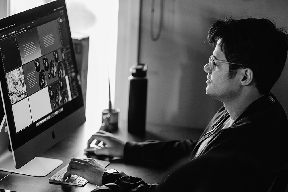 man working on his mac desktop working on graphic design layouts