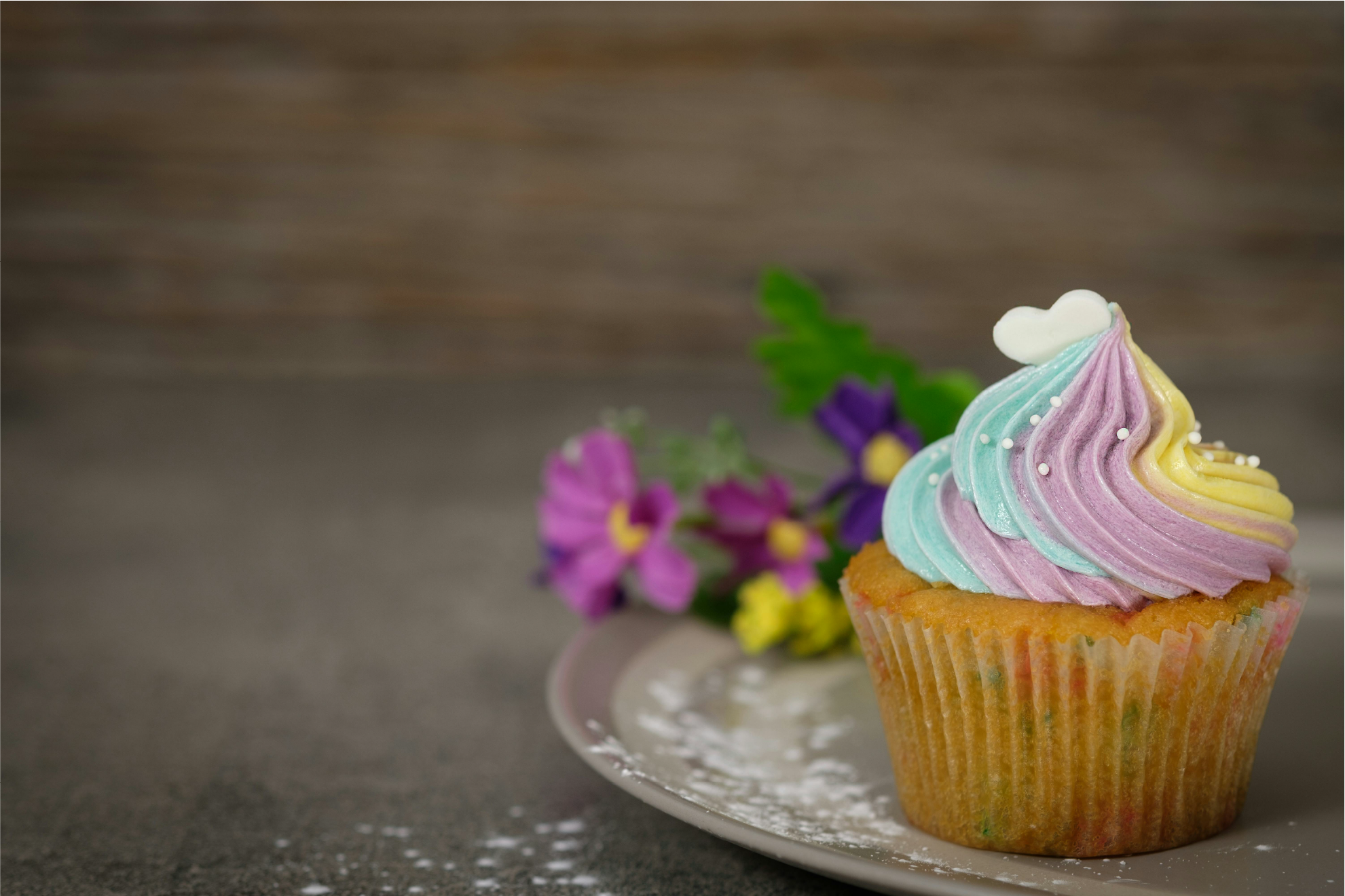 a colorful single cupcake on a plate with flowers